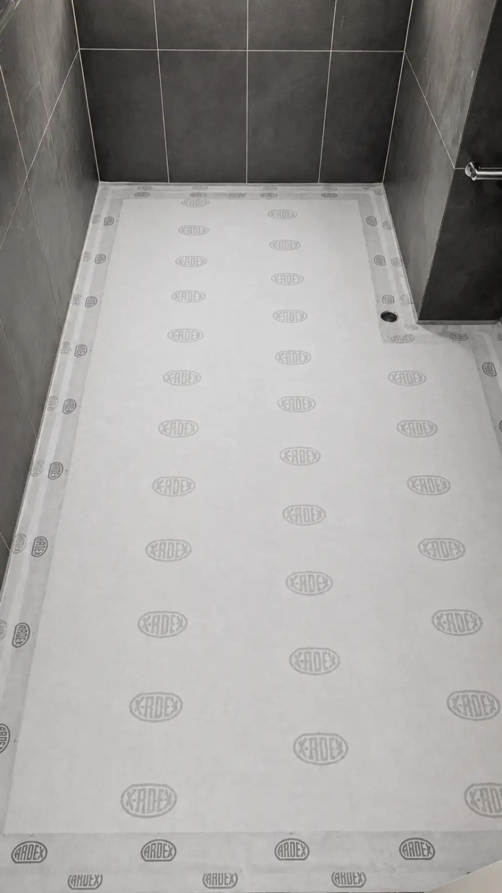 Professional installer applying ARDEX WPM waterproofing membrane to a concrete surface